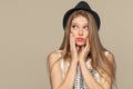 Surprised happy beautiful young woman looking up in excitement. Fashion girl in hat. isolated on beige background Royalty Free Stock Photo