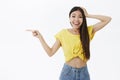 Surprised happy and delighted good-looking female with long dark hair in cropped yellow t-shirt holding hand on head