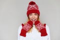 Surprised happy woman looking sideways in excitement. Christmas girl wearing knitted warm hat and mittens, isolated on gray backgr