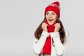 Surprised happy woman looking sideways in excitement. Christmas girl wearing knitted warm hat and scarf, isolated on gray Royalty Free Stock Photo