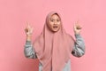 Surprised happy young  asian muslim woman in hijab pointing overhead on workspace area copy space Royalty Free Stock Photo