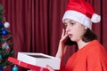 Surprised and happy young woman in Santa hat and red sweater opens a Christmas present box Royalty Free Stock Photo