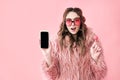 Surprised hipster woman holding blank screen mobile phone over pink background Royalty Free Stock Photo