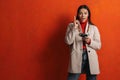 Surprised hispanic woman pointing finger upward while using cellphone