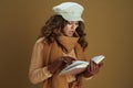 Surprised housewife in sweater reading book isolated on beige Royalty Free Stock Photo