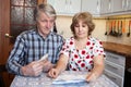 Surprised husband and wife looking at bills with cash money in hands, domestic kitchen Royalty Free Stock Photo