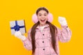 surprised kid in winter earmuffs with box. teen girl in mittens hold present