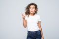 Surprised latin woman with curly hair pointing at copy space isolated over white background Royalty Free Stock Photo