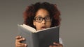 Surprised little black girl with book at gray background Royalty Free Stock Photo