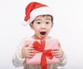 Surprised  little  boy dressed in christmas Santa hat and holding gift Royalty Free Stock Photo