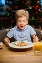 Surprised little boy eating festive meal during Christmas dinner in restaurant Royalty Free Stock Photo