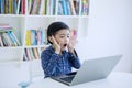 Surprised little boy using a laptop in the library