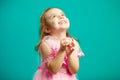 Surprised little girl in beautiful pink dress clasped hands in front of her and looks up happily, portrait on