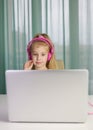 Surprised little girl with headphones using laptop and watch cartoon Royalty Free Stock Photo