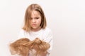 A surprised girl holds in hands cropped hair after cutting on a white background