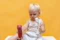 A surprised little girl holds a wired telephone receiver in her hands and does not know what to do with them