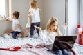 Surprised little girl with a laptop, and her younger brother and sister playing in the background Royalty Free Stock Photo