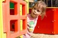 Surprised little girl peeking out of a small house on the playground Royalty Free Stock Photo