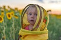 Surprised little girl wearing a beekeeper mask against the backdrop of a field with sunflowers. Beekeeping concept