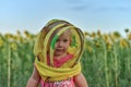 Surprised little girl wearing a beekeeper mask against the backdrop of a field with sunflowers. Beekeeping concept