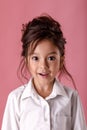 Surprised little girl in white shirt with hairstyle looking to camera