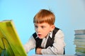 Surprised little schoolboy among notebooks and textbooks at his desk at school in the classroom Royalty Free Stock Photo