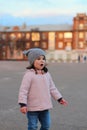 surprised little white girl walking down the street in the evening. Portrait on the background of the sunset cityscape Royalty Free Stock Photo