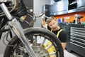 Surprised male repairman scratching his head with spanner and looking at motorcycle Royalty Free Stock Photo