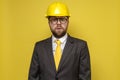 Surprised man in a construction helmet and a suit anxiously looks into the camera with big eyes and mouth open.