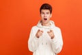 Surprised man in fashionable hoodie widely opening eyes and mouth saying wow and pointing fingers at you. Amazed with news, Royalty Free Stock Photo