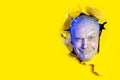 Surprised man looking through hole in yellow paper. Copy space for advertise Royalty Free Stock Photo