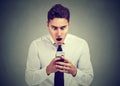 Surprised man looking at phone seeing unexpected news or photos with wonder emotion on face Royalty Free Stock Photo