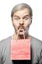 Surprised mature man with shopping bag in mouth isolated