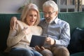 Surprised mature wife and husband using tablet, reading pleasant news Royalty Free Stock Photo