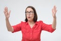 Surprised mature woman in glasses and red clothes making hands the size of big thing