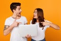 Surprised man and woman holding and pointing at laptop Royalty Free Stock Photo