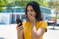 Surprised mexican young adult woman with phone receiving message with good news Royalty Free Stock Photo