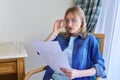 Surprised middle aged woman with glasses reading papers sitting at home in chair Royalty Free Stock Photo