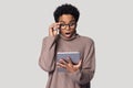 Surprised millennial affrican american woman looking at digital tablet screen.