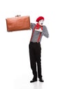 surprised mime showing at brown suitcase