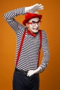Surprised mime with white face in red hat and striped t-shirt on blank orange background Royalty Free Stock Photo