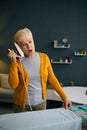 Surprised old woman keeping iron like phone