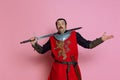 One young man, medieval warrior or knight wearing wearing armor clothing posing  over pink background Royalty Free Stock Photo