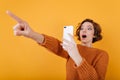 Surprised pale girl with surprised face taking picture of someone. Indoor portrait of amazed young woman in sweater Royalty Free Stock Photo