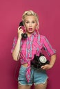 Surprised Pinup woman answers a phone call. Beautiful retro model with red lips makeup and old fashion hairstyle Royalty Free Stock Photo