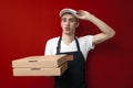 Surprised pizza delivery man gives boxes on a red background, shocked courier delivers an order Royalty Free Stock Photo