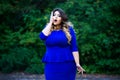 Surprised plus size fashion model in blue dress outdoors, beauty woman with professional makeup and hairstyle Royalty Free Stock Photo