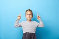 Surprised pretty little girl pointing with two fingers to up, looking to up, isolated on blue Royalty Free Stock Photo