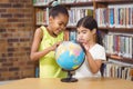 Surprised pupils studying globe in the library Royalty Free Stock Photo