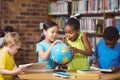 Surprised pupils studying globe in the library Royalty Free Stock Photo